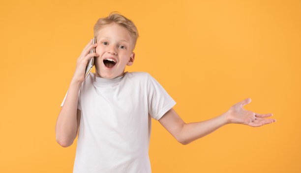 兴奋的男孩一边打电话一边打手势图片下载