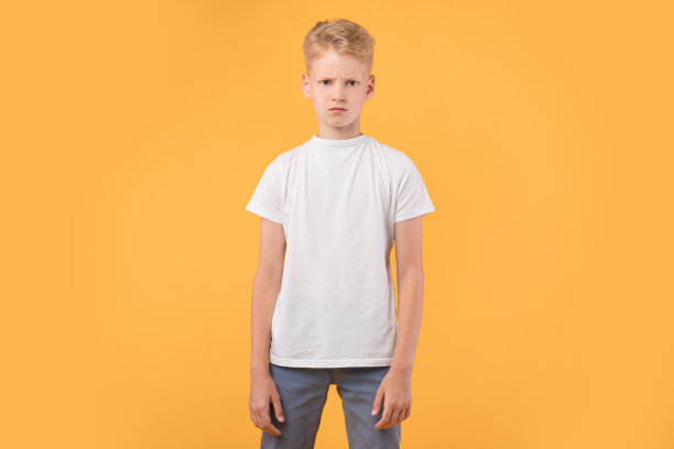 一幅悲伤愤怒的男孩站在工作室橙色墙壁前的肖像图片下载