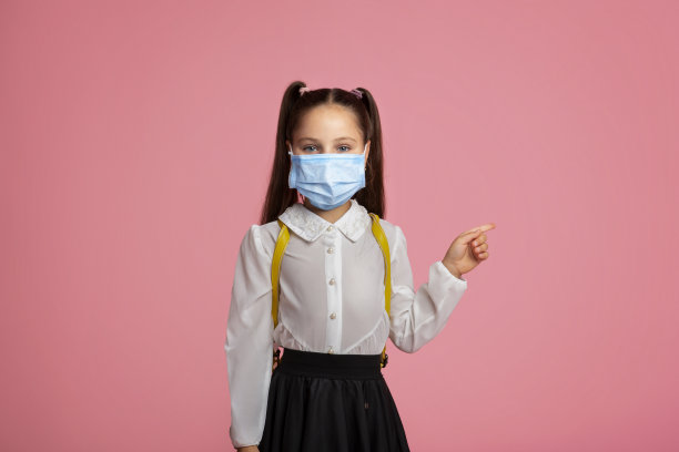 疫情隔离期间的教育。穿制服戴防护面具的女童图片下载