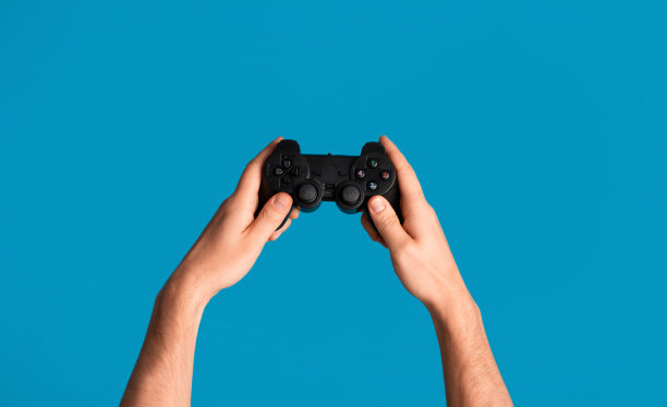 年轻人拿着电子游戏操纵杆在蓝色的背景，手的特写图片下载