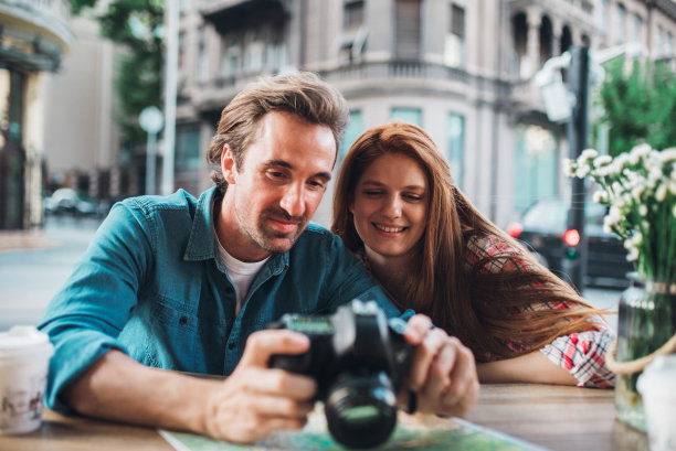 这对幸福的情侣正在休息，喝咖啡，看他们在旅途中拍的照片图片下载