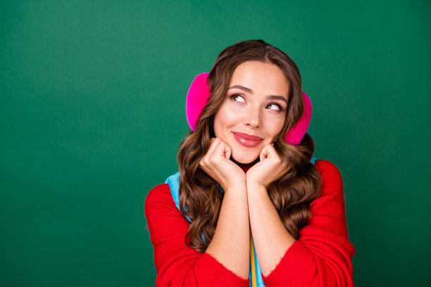 近距离的肖像照片可爱迷人的梦幻的年轻女士手握脸向上看空的空间想象未来的暑假穿粉红色的耳朵加热器红色毛衣孤立的绿色背景图片下载