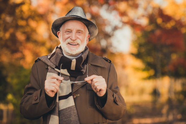 滑稽的照片，高兴的老人，白发的爷爷，中央公园散步，享受阳光明媚的日子，温暖的天气，牙齿，微笑，抱眼镜，戴时尚的秋天夹克，帽子，围巾，多彩的街道外面图片下载