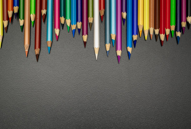 教育背景。学校文具用彩色的铅笔、粉笔、毛笔在教室的黑色黑板上。旗帜概念回到学校。图片下载