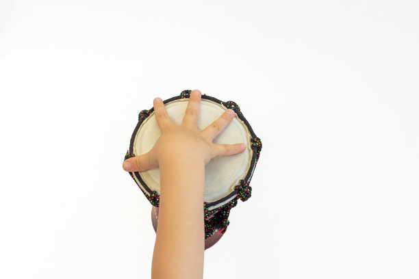 孩子们的手在白色背景下打鼓。儿童演奏乐器的技能。音乐教育图片下载