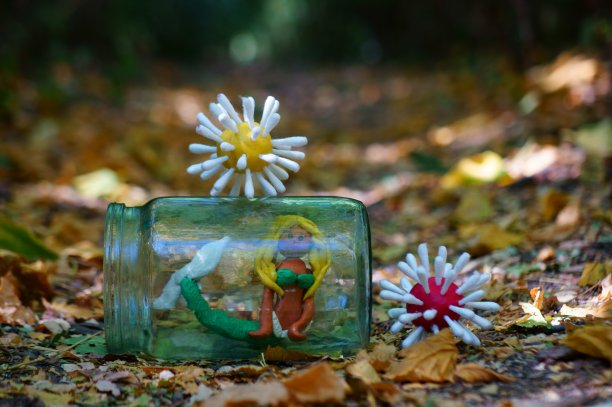 用粘土做的病毒雕像。旁边是一个装在玻璃罐里的小美人鱼。图片下载