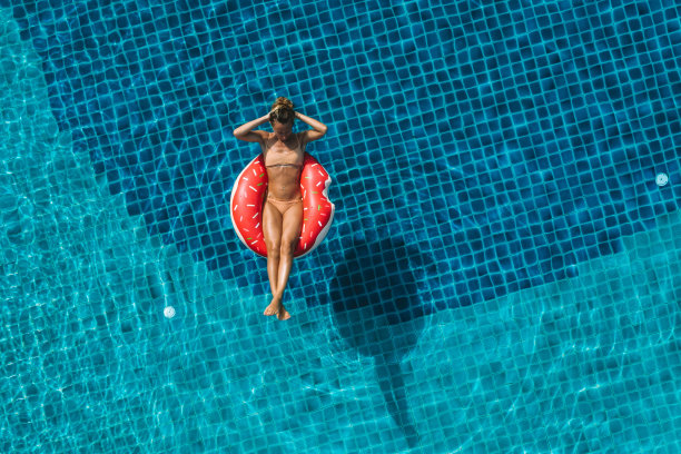 在游泳池里，一个女人漂浮在充气筏上图片下载