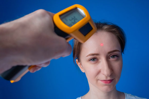 男人手拿高温计，测量微笑女人的温度:近距离观察图片下载