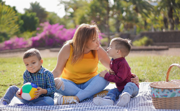 母亲和她的两个儿子在公园里享受这一天，在大自然中拍一张照片-快乐的母亲亲吻她的儿子-母亲，孩子和家庭的爱图片下载