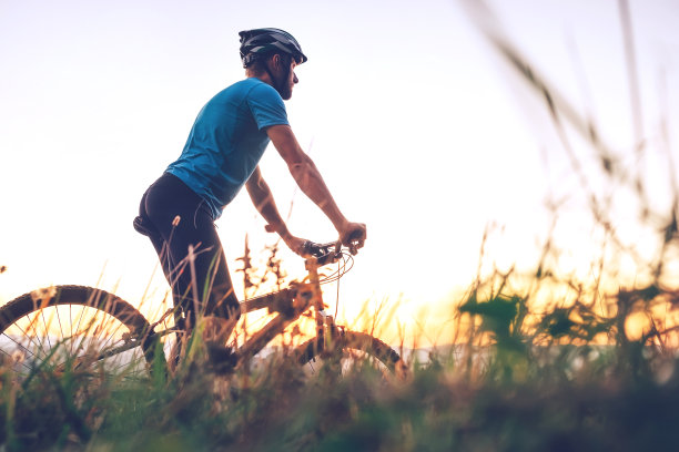 一个骑自行车的男人在城市的山顶上遇到了夕阳。积极运动的人概念形象图片下载