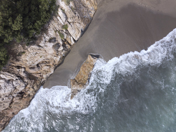 鸟瞰图一个孤立的海滩，沙子和白嘴鸦的特写。在空旷的海滩上，海浪拍打着岩石。Nerja,西班牙马拉加图片下载