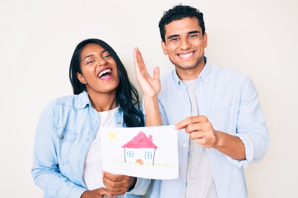 美丽的拉丁年轻夫妇展示房子项目在纸上庆祝胜利与快乐的微笑和胜利者的表情与举手图片下载