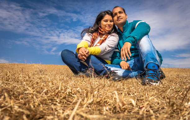 一对情侣在美丽的黄草和蓝天的背景下表达爱意图片下载