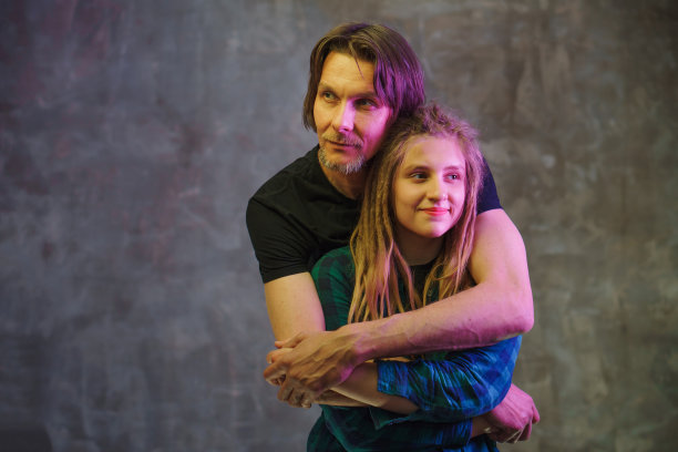 男子和年轻女子与彩色灯光在黑暗的背景摆姿势。图片下载