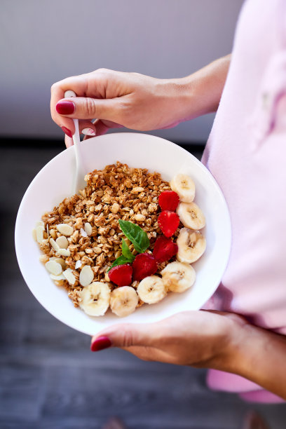 女人吃着健康的早餐，手里捧着碗图片下载
