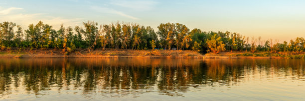 夏日美景如画，夕阳下的河岸尽收眼底。平静的平原江水，倒影在水中。奇妙的自然，美丽的自然背景。俄罗斯阿斯特拉罕地区的Akhtuba河图片下载