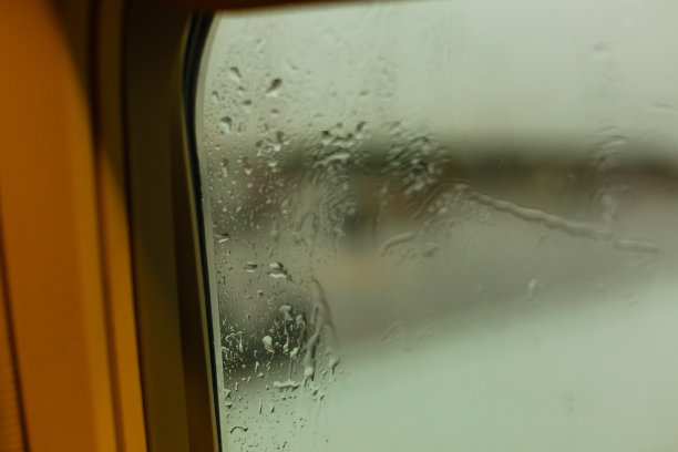 模糊的照片，雨滴从飞机窗户和机场跑道的背景。图片下载