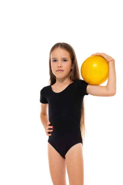 图片的一个体操女孩在白色短袜和黑色trico全高度站在黄色球在她的手孤立在一个白色的背景图片下载