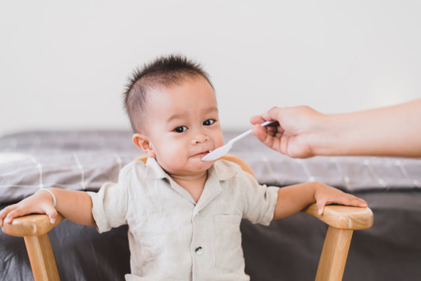 早上，妈妈在家里给可爱的亚洲宝宝递食物图片下载