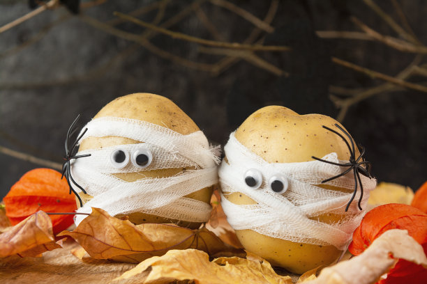 万圣节的背景。木桌上裹着医用绷带的吓人的土豆。万圣节的食物。禁令。空间的拷贝。图片下载