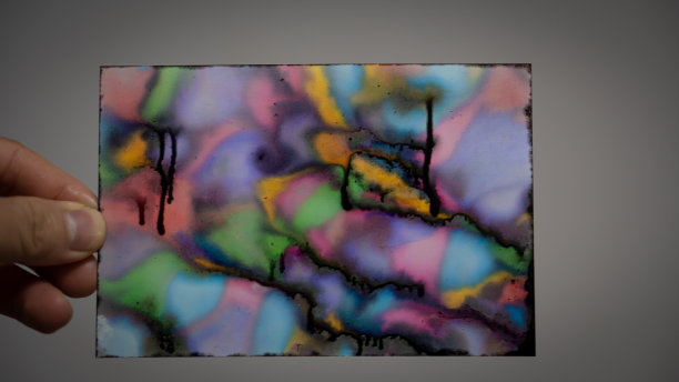 手握被打印机染污的纸和五颜六色的花样，美丽的白色墙壁背景。图片下载