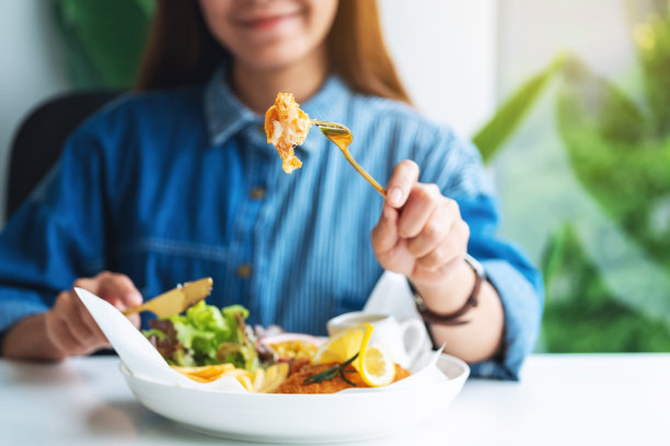 一个美丽的亚洲女人在餐馆的桌子上吃鱼和薯条图片下载