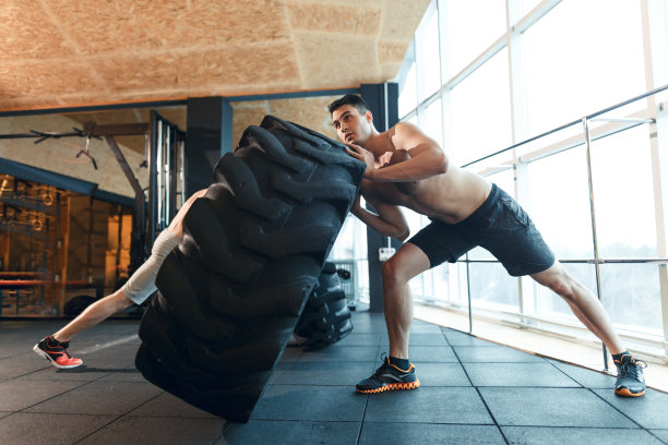 两个年轻人在健身房翻轮胎图片下载