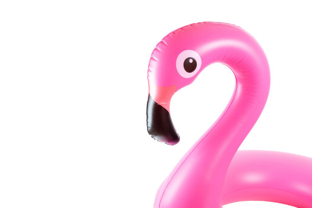 夏天有趣的海滩。粉红色的游泳池充气火烈鸟夏天海滩孤立在白色的背景。有趣的小鸟玩具的孩子。图片下载