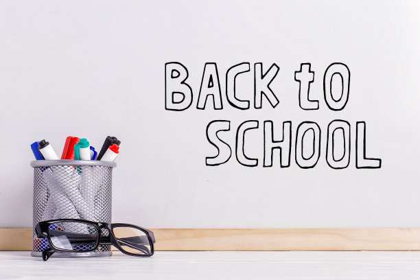 马克笔，眼镜和一块白板。白板上的题词是“回到学校”。图片下载