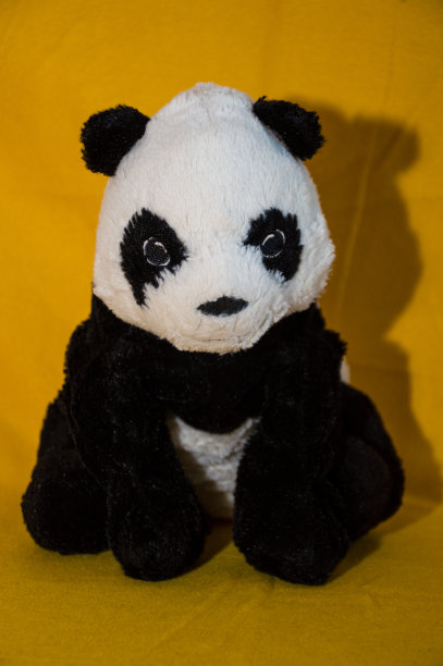 黄色背景上的毛绒玩具熊猫图片下载