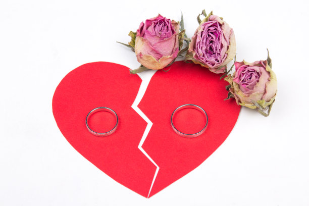 离婚概念-婚戒在红色的破碎的心与干花孤立在白色图片下载