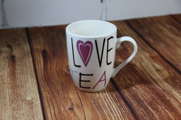 木桌上有一个刻有“我爱茶”字样的杯子图片下载