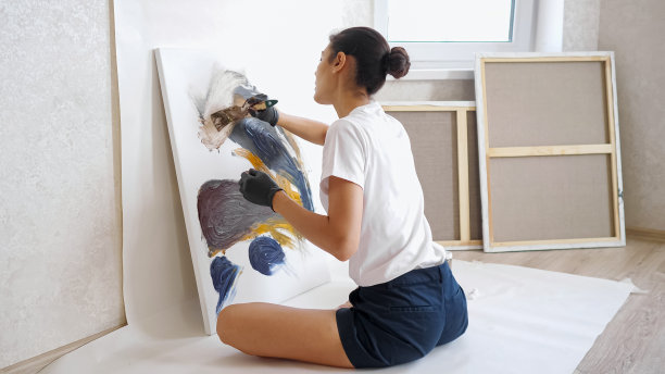 优雅的艺术家以瑜伽姿势坐在木地板上作画图片下载