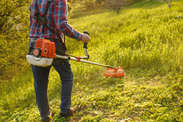 在日落时分，工人在绿色的院子里割草图片下载