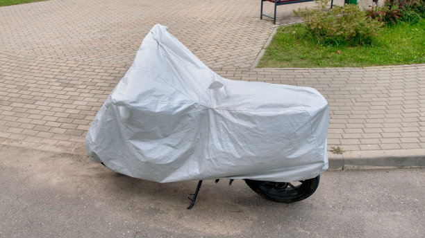 在恶劣的雨天，摩托车被白色密集的纺织箱覆盖图片下载