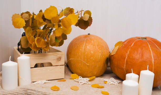 秋天的家居装饰。秋天陪伴的南瓜，蜡烛，树叶。设计的空白。内部的想法。图片下载