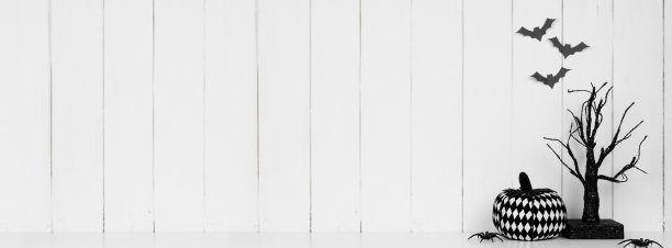 黑色和白色的万圣节装饰在架子上靠白色的木制墙板和蝙蝠图片下载