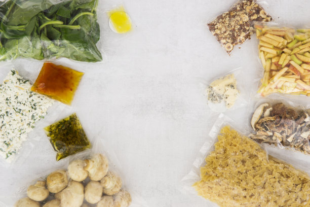 一套意大利晚餐产品:意大利面，菠菜，蘑菇，苹果，坚果，橄榄油，酱料和香料。一套送晚餐食物的餐具。在家做饭，在家做饭。平的。图片下载