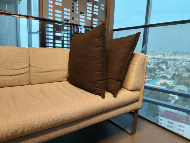 舒适的角落装饰皮革皮色沙发与枕头的房子客厅和发光拥挤的城市，装饰背景图片下载