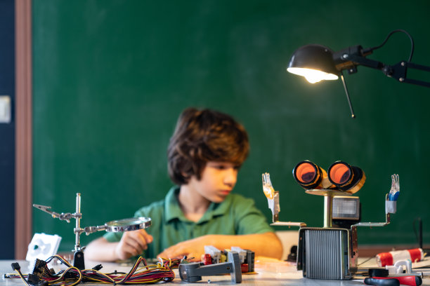 一个小学生在绿色黑板前研究机器人和编程图片下载