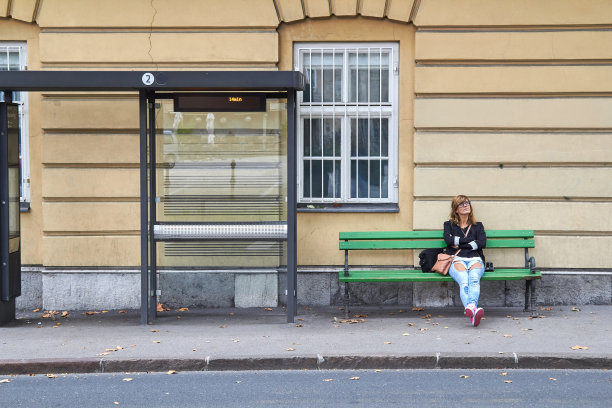 一个年轻的白人女人在车站等公共交通工具。图片下载