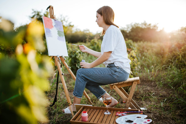 一个年轻女子喝着酒，在大自然中作画图片下载