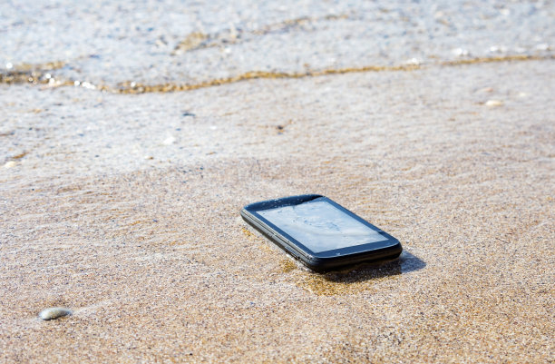 度假时在海边丢了智能手机。寻找丢失的东西，修复溺亡的手机，概念形象。图片下载