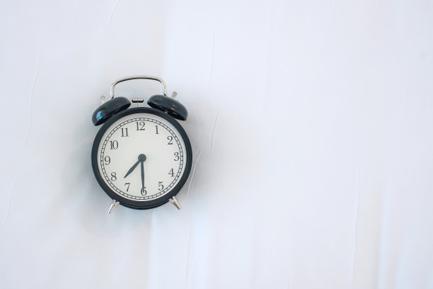黑色复古闹钟在床上，早上醒来，清新放松，有一个美好的一天和日常的概念图片下载