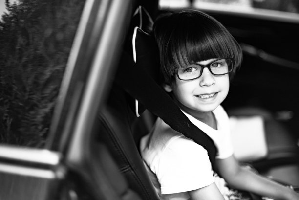 一个戴眼镜的孩子正坐在汽车里。图片下载