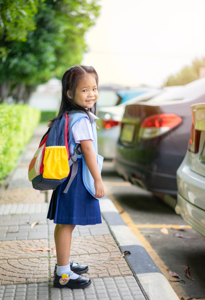 快乐的小女孩穿着泰国校服站在公园里，准备回学校图片下载