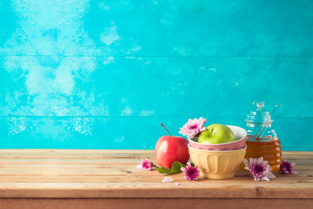 犹太节日犹太新年的背景是蜂蜜罐，苹果和鲜花放在木桌上图片下载