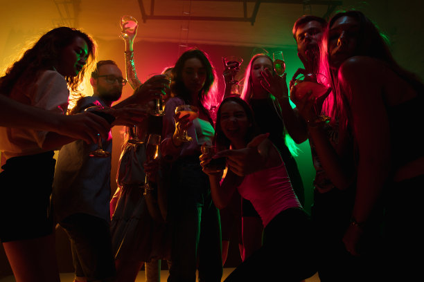 一群剪影般的人在霓虹灯背景下的舞池上举手图片下载