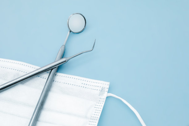 医用口罩和一套蓝色背景的金属牙科保健器械。有选择性的重点图片下载
