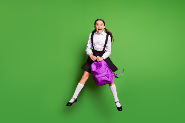 照片肖像疯狂的女孩尖叫跳起抱着紫色的书包孤立在鲜艳的绿色背景图片下载